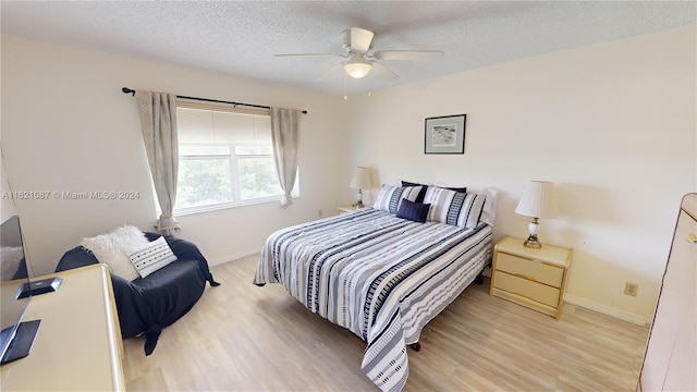 bedroom featuring light wood-type flooring, ceiling fan, and a textured ceiling