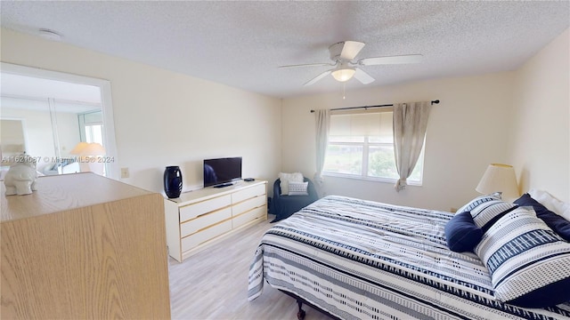 bedroom featuring ceiling fan, a textured ceiling, and light wood-type flooring