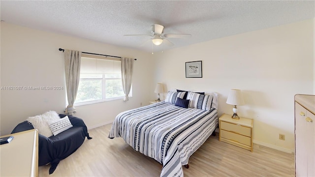 bedroom with ceiling fan, a textured ceiling, and light hardwood / wood-style floors