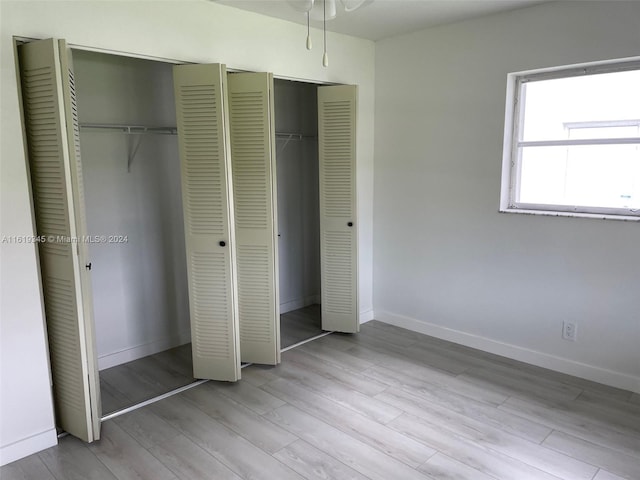 unfurnished bedroom with light wood-type flooring and multiple closets