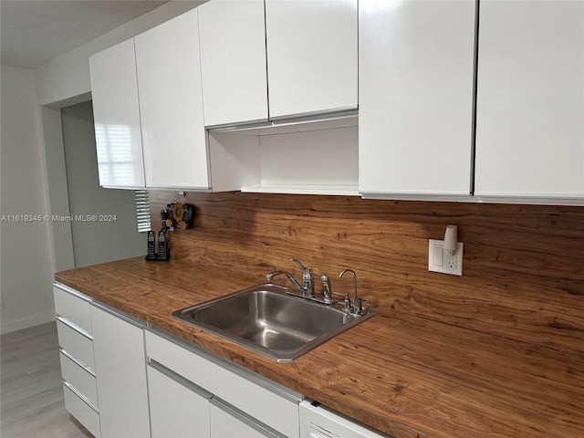 kitchen with white cabinetry, sink, and light hardwood / wood-style flooring