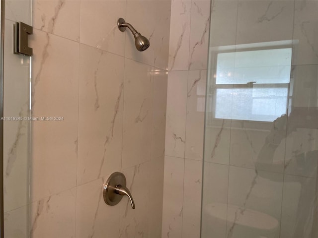 bathroom featuring tiled shower and toilet