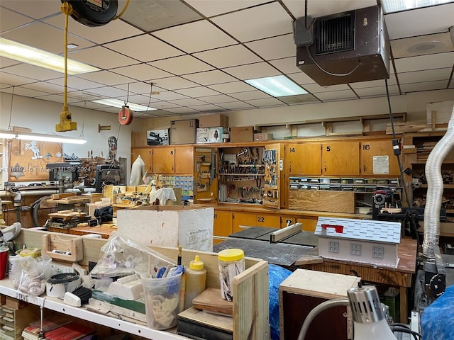 miscellaneous room featuring a drop ceiling and a workshop area