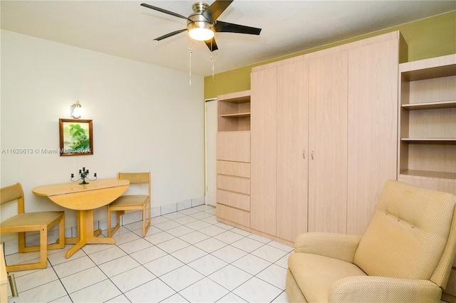 kitchen featuring tasteful backsplash, ceiling fan, range with electric stovetop, light tile patterned floors, and a kitchen breakfast bar