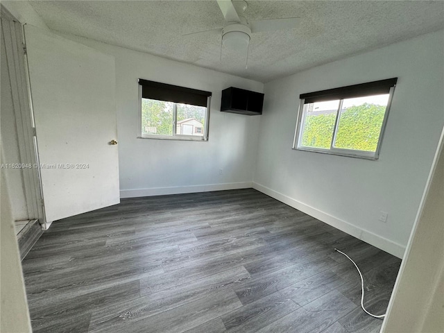 empty room with ceiling fan, a textured ceiling, and dark hardwood / wood-style flooring