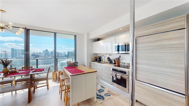 kitchen featuring light wood-type flooring, sink, stainless steel appliances, and white cabinets