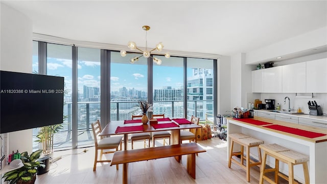 dining area featuring sink, expansive windows, light hardwood / wood-style floors, and a notable chandelier