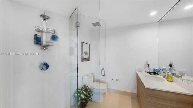 bathroom featuring a shower with door, toilet, vanity, and tile patterned floors