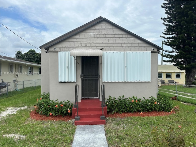 bungalow-style house with a storage unit and a front yard