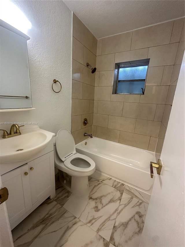 full bathroom featuring a textured ceiling, tiled shower / bath, vanity, and toilet