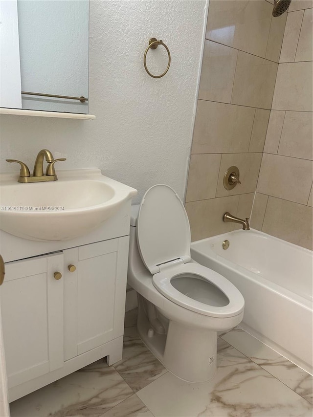 full bathroom featuring tiled shower / bath, vanity, and toilet