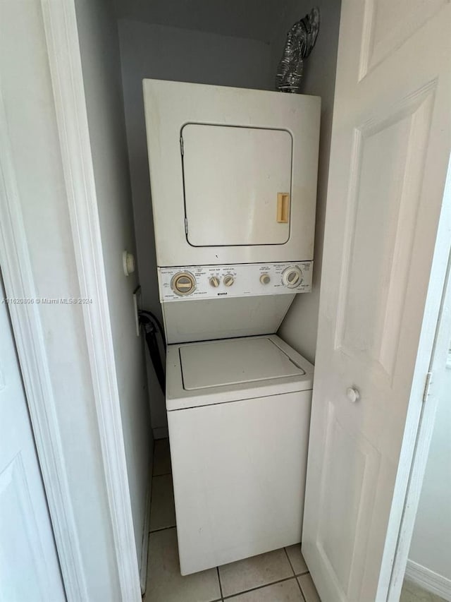 laundry room featuring stacked washer and dryer and light tile patterned floors