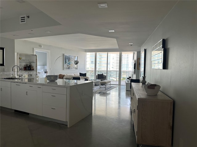 kitchen with white cabinets, dark tile patterned flooring, floor to ceiling windows, and sink