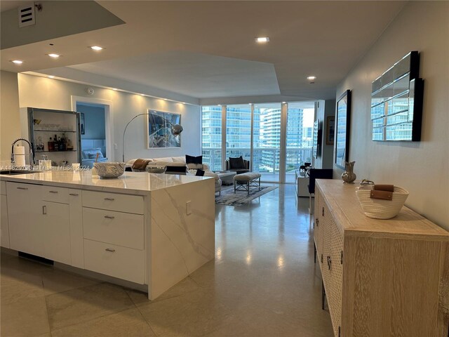 kitchen featuring sink, white cabinets, a kitchen island, and light stone countertops