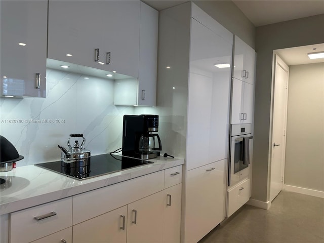 kitchen with white cabinets, oven, and black electric cooktop