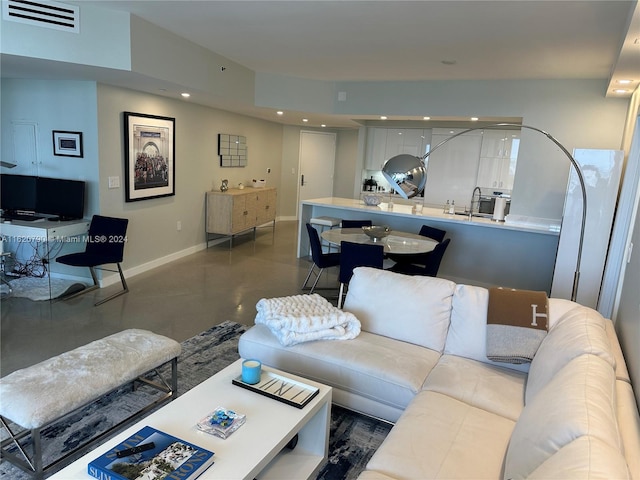 living room with finished concrete floors, recessed lighting, visible vents, and baseboards