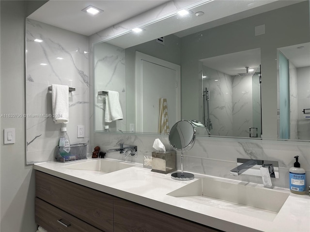 bathroom with double vanity, backsplash, a sink, and a marble finish shower