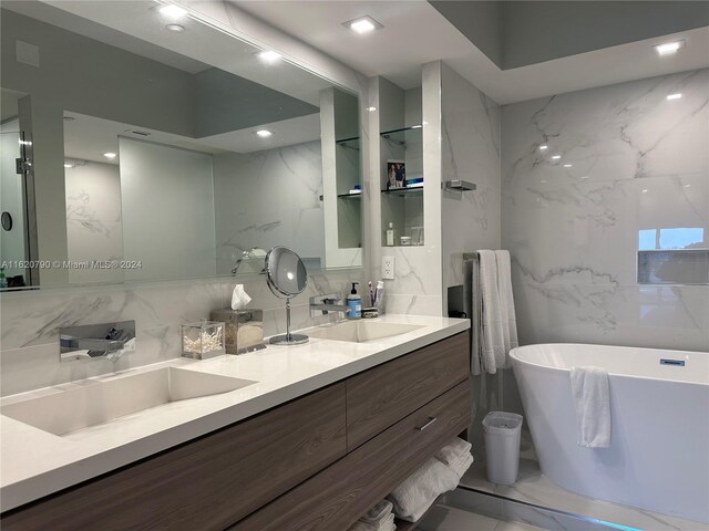 bathroom featuring dual vanity, tile patterned floors, a washtub, and tile walls