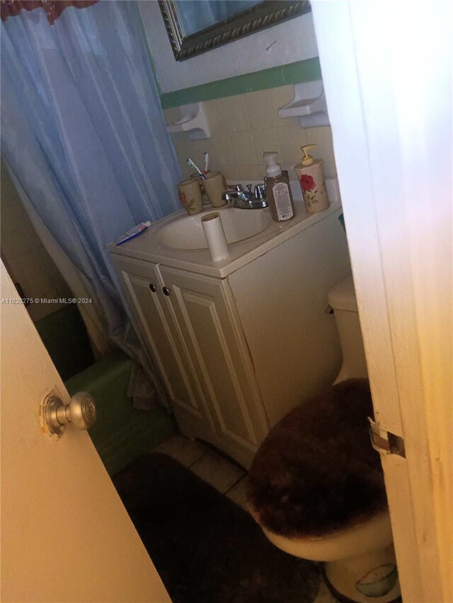 bathroom with tile patterned flooring, toilet, sink, and tasteful backsplash