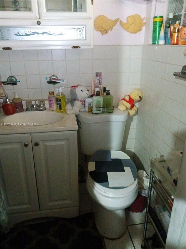 bathroom with decorative backsplash, vanity, toilet, and tile walls