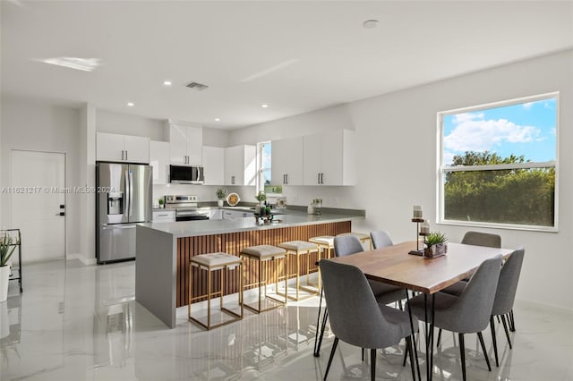 kitchen featuring a kitchen breakfast bar, white cabinetry, kitchen peninsula, and stainless steel appliances