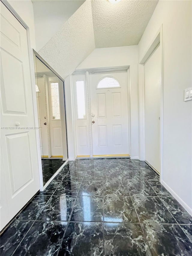 foyer with a textured ceiling and vaulted ceiling