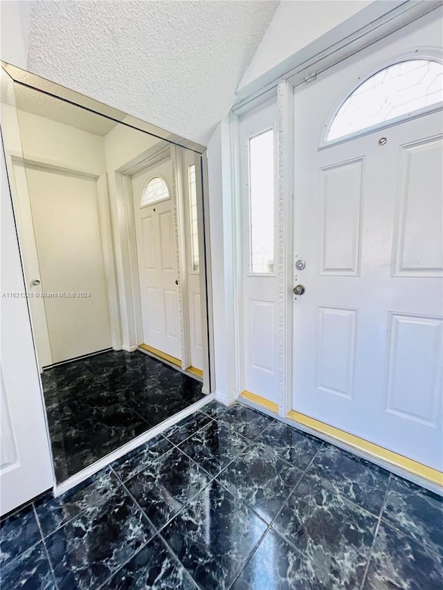 entrance foyer with vaulted ceiling and a textured ceiling