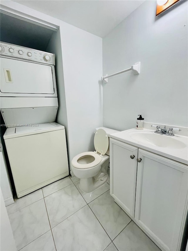 bathroom featuring toilet, vanity, stacked washer and dryer, and tile patterned flooring