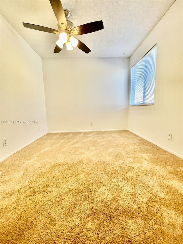 carpeted empty room featuring a textured ceiling and ceiling fan