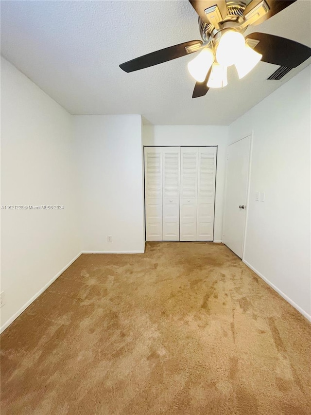 unfurnished bedroom with ceiling fan, a closet, and carpet floors