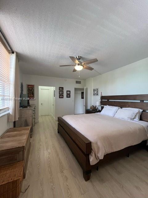 bedroom with hardwood / wood-style flooring, a textured ceiling, and ceiling fan