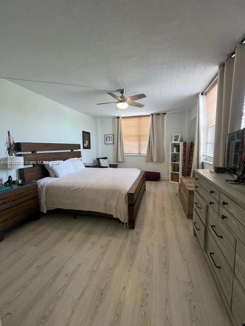 bedroom featuring light hardwood / wood-style flooring, a textured ceiling, and ceiling fan