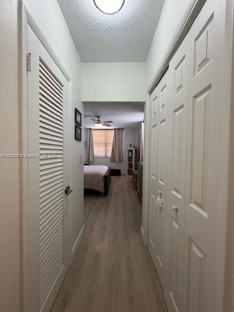 corridor with a textured ceiling and hardwood / wood-style flooring