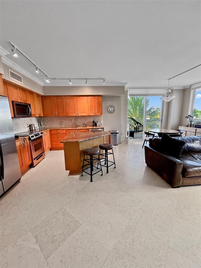 kitchen with appliances with stainless steel finishes, a kitchen bar, light tile patterned floors, and track lighting