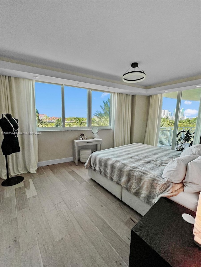 bedroom featuring multiple windows, access to outside, and light wood-type flooring