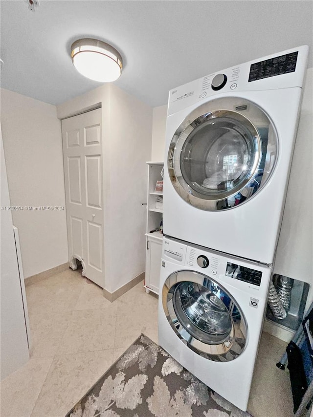 clothes washing area with stacked washer / drying machine and light tile patterned floors