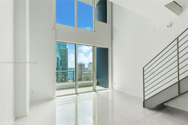 spare room with a high ceiling and light tile patterned flooring