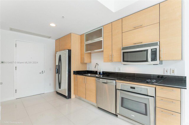 kitchen with light brown cabinetry, appliances with stainless steel finishes, light tile patterned floors, and sink