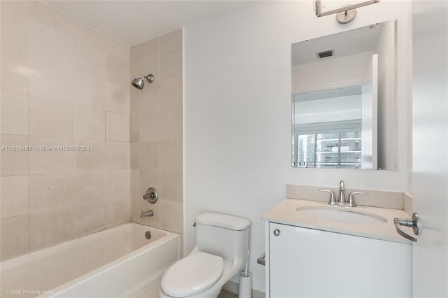 full bathroom featuring vanity, tiled shower / bath, and toilet