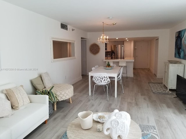 dining room with light hardwood / wood-style floors and a notable chandelier