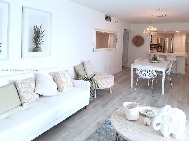 living room with light wood-type flooring and a chandelier