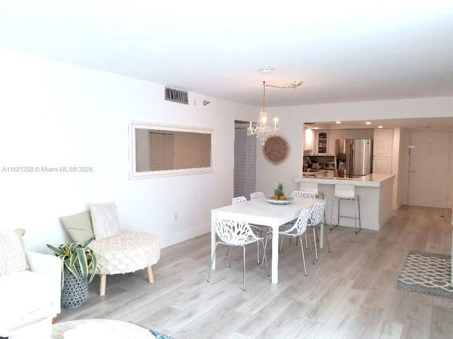 dining area featuring light hardwood / wood-style floors and a chandelier