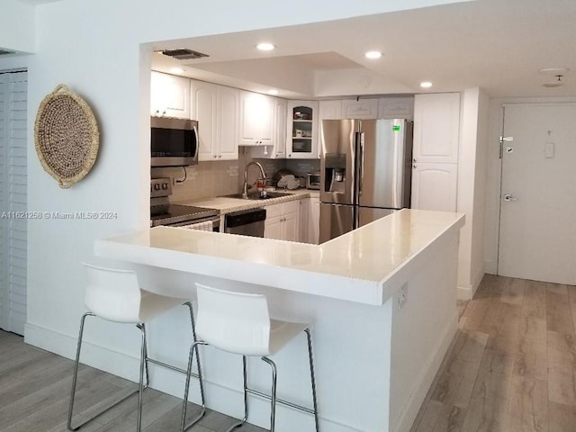 kitchen featuring appliances with stainless steel finishes, light hardwood / wood-style flooring, tasteful backsplash, and white cabinetry