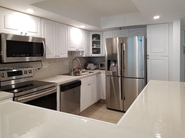 kitchen with sink, decorative backsplash, stainless steel appliances, and white cabinets