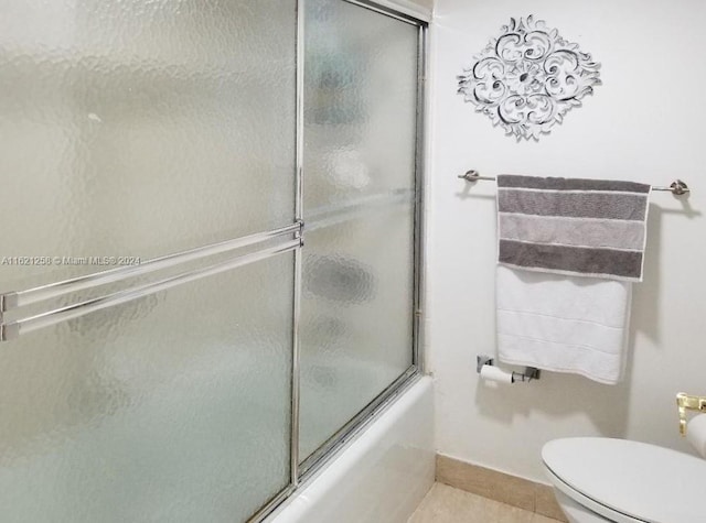 bathroom with tile patterned flooring, toilet, and shower / bath combination with glass door