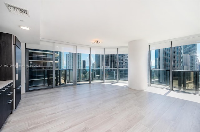 empty room featuring floor to ceiling windows and light wood-type flooring