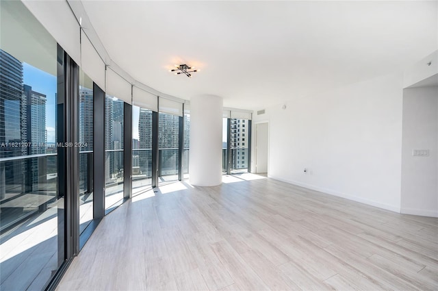 spare room with floor to ceiling windows and light hardwood / wood-style flooring