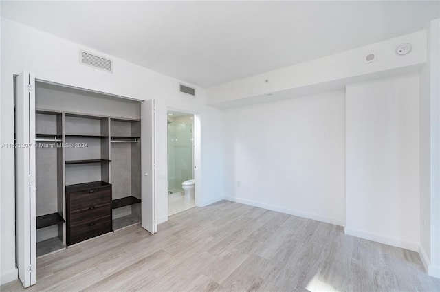 unfurnished bedroom featuring connected bathroom, light hardwood / wood-style flooring, and a closet