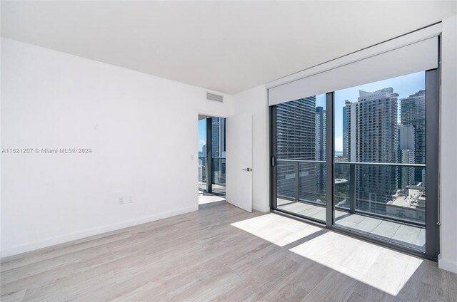 unfurnished room with light hardwood / wood-style floors and a wall of windows