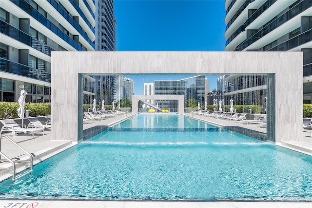 view of pool featuring pool water feature and a patio